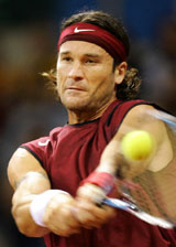 Spains Carlos Moya returns a backhand to Mardy Fish of the USA during the first match of the 2004 Davis Cup final at Sevilles Olympic Stadium 