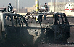 Iraqi policemen stand guard after gunmen fired mortars at a police station in Baghdad's Seydiya district on Friday
