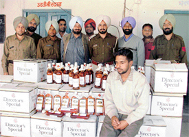 Accused Jassi Puri seen in the custody of the Sunder Nagar police with the recovered cases of liquor bottles