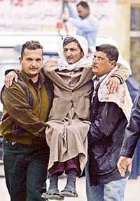 Iraqis carry an elderly man away from the scene of an early morning car bomb attack, which went off near a police station beside the heavily protected Green Zone, in central Baghdad