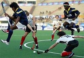 Indian players V.S. Vinaya and Arjun Halappa are airborne while German defender Till Kriwet clears the ball 