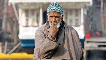 A Kashmiri man looks out pensively from the banks of Dal Lake in Srinagar