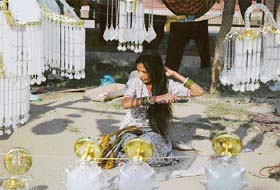 A woman combs her hair as she sells chandeliers on the Pakhowal road