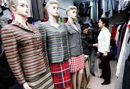 A Chinese shopkeeper takes a customers measurements at a textile market in Shanghai on Monday.