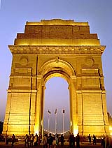 People walk around the historic India Gate during the evening