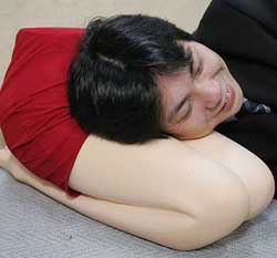 Japanese toy maker Trane Cos Managing Director Makoto Igarashi rests his head atop his creation called the lap pillow, a polyurethane pillow shaped like a kneeling woman from the waist-down in Tokyo on Wednesday.