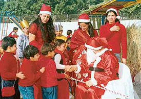 A teacher dressed as Santa Claus shakes hands with tiny tots of Kids-R-Kids School in Chandigarh on Friday.