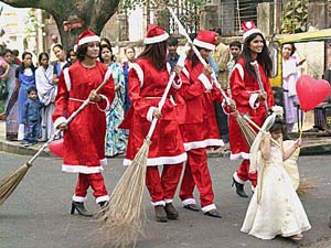 Models dressed as Santa clean up city streets with brooms