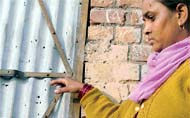 A woman shows bullet marks on the gate in Ludhiana on Saturday