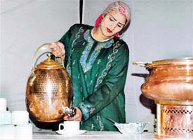 A woman attired in a Kashmiri dress serves kahwa to members of the Sutlej Club 