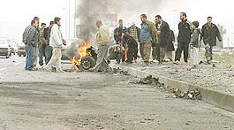 Onlookers view a crater in the road