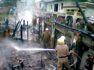 Firefighters try to douse the fire which gutted shops and houses at McLeodganj in Dharamsala on Monday.