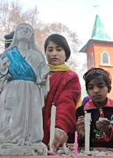 A woman and her son light candles at a church on the occasion of Christmas in Srinagar on Saturday.