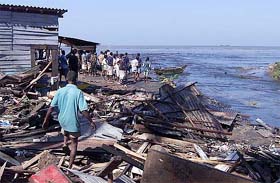 People walk through the debris of their houses destroyed in tidal waves on the coastal areas in Colombo, Sri Lanka