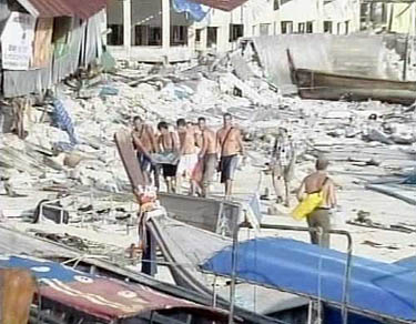 A frame grab taken from video footage shows foreign tourists (centre) as they stretcher an injured person along a destroyed beach on Phi Phi island, Thailand, on December 26, following a large earthquake.  Reuters