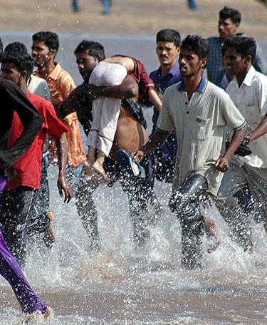 Locals and rescuers carry a girl from the Marina beach after a tsunami hit Chennai on December 26.  Reuters
