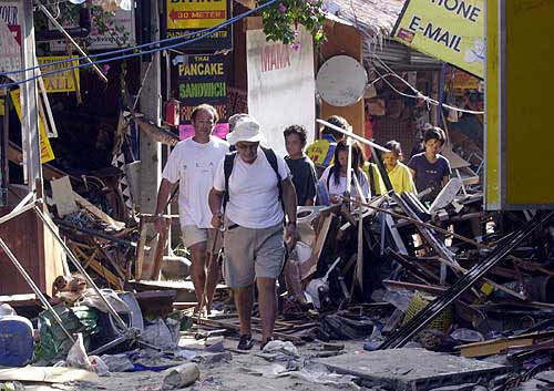 Tourists make their way through a damaged business area on the Phi Phi Island after giant waves swept through this famous tourist resort in Krabi province, southern Thailand, on December 27.  AP/PTI