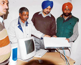 Policemen examine a computer used by operators of an illegal telephone exchange at Feroze Gandhi Market in Ludhiana