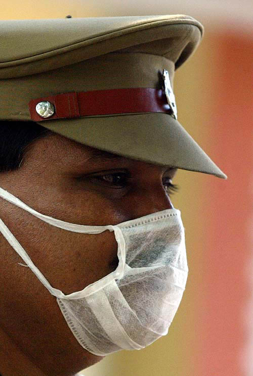 An Indian policeman wears a mask while handing back the bodies of victims of Sunday's tsunami to their relatives at a mortuary in Cuddalore, 180 km south of Chennai on December 28.  Reuters