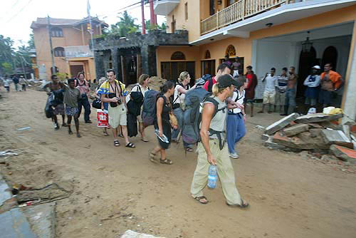 Tourists walk in Unawatuna near the southern Sri Lankan city of Galle to a waiting bus bound for the capital Colombo on December 28, 2004. Over 300 tourists were evacuated on Tuesday from the devastated town by buses arranged by the British High Commission.  While most tourists scrambled to escape the carnage, taking helicopter flights and sea-planes organised by their embassies, many foreigners who have made their homes in Sri Lanka weighed in to help.   Reuters