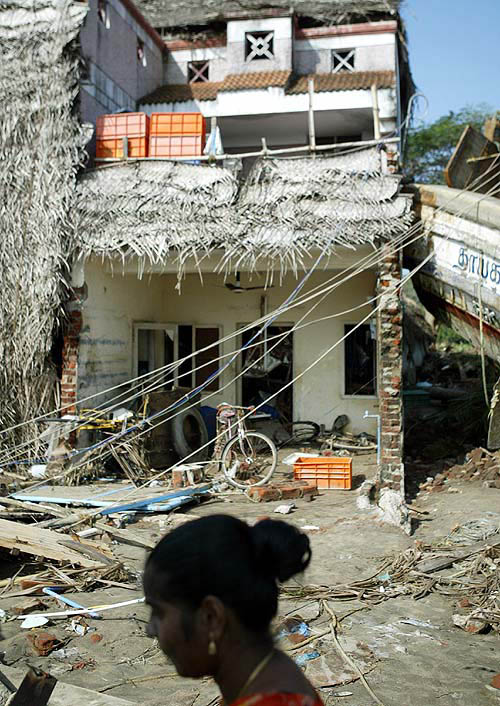 A woman walks pass a damaged house hit by tsunami near Nagapattinam port, 350 km south of Chennai, on December 28.  Reuters