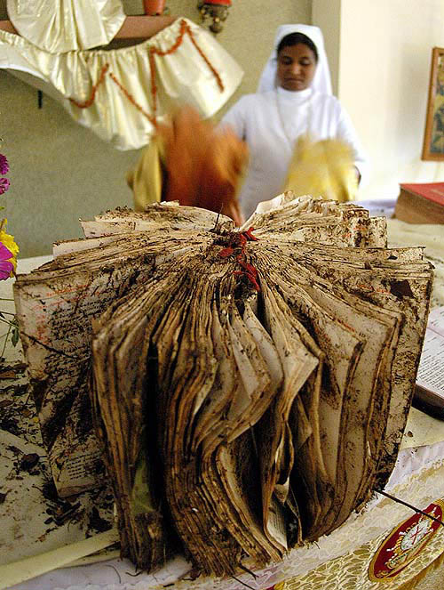 A nun looks at the still wet Bible inside the St. Antony Church in Kalpakkam, 70 Km from Chennai, on December 28, two days after a tsunami hit the area.  Reuters