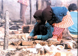 Children play with their charred toys in what remains of their slum cluster in Geeta Colony, the site of a fire in the wee hours