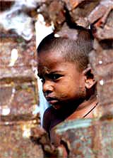 A boy looks through a demolished wall at a relief camp in Chennai on Sunday