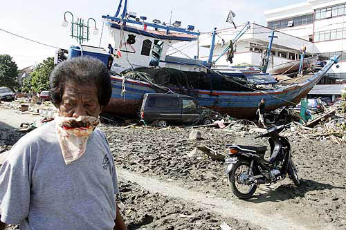 A man walks past a fishing boat left on a street in Banda Aceh, Indonesia, on December 29 after the area was hit by a tsunami on Sunday.  Reuters
