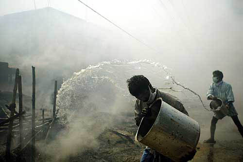 Indian survivors of Sunday's tsunami pour water on their houses which caught fire from the flames of a nearby funeral pyre in Nagapattinam port, 350 km south of Chennai, on December 29.  Reuters
