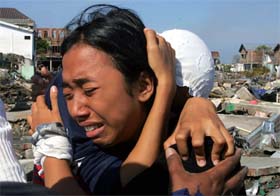 An Acehnese girl cries with her mother near the ruins of their house in Banda Aceh