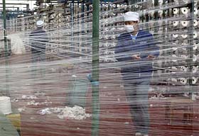 A worker at the state-owned Shijiazhuang Changshan Textile factory inspects strands of cotton thread in the mechanised process of producing quality fabric for export