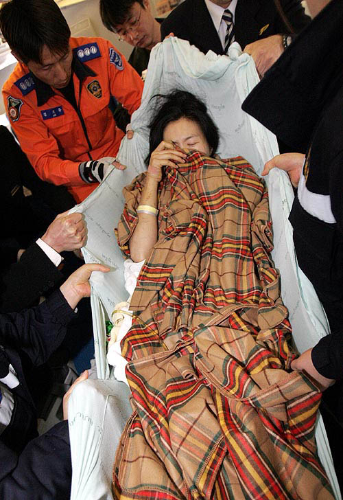 Employees at Inchon airport carry a South Korean woman injured by Sunday's quake-triggered tidal wave in Phuket, in Inchon, west of Seoul, on December 30. Up to five million people around the Indian Ocean waited for food and clean water on Thursday as nations hit by one of the biggest tsunamis on record rush to bury their dead and avert the threat of disease.  Reuters