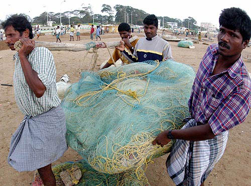 Fishermen carry their fishing nets at the Marina beach after the tsunami hit on Sunday in Chennai on December 30.  Reuters
