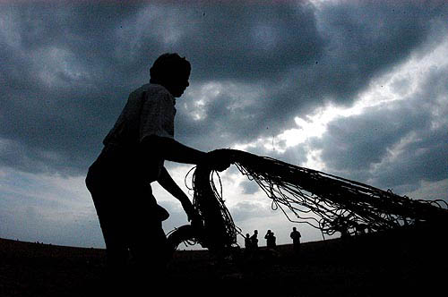 A fisherman repairs his fishing net at the Marina beach after the tsunami hit on Sunday in Chennai on December 30.  Reuters