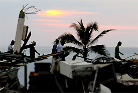 Local volunteer rescue workers walk home as the sun sets over the wrecked resort town of Khao La