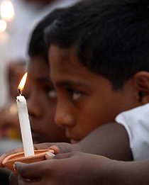 Sri Lankan children hold candles at a national prayer service in memory of the thousands of Sri Lankan people who perished when a giant tsunami hit coastal areas in Colombo, Sri Lanka on Friday