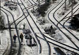 Chinese workers walk along snow covered railway tracks in Shanghai on Saturday as Chinas commercial stronghold has forced more than 800 companies to shift production after an unseasonal cold snap and snow left the power grid groaning under surging demand, state media said. 