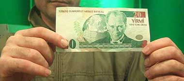 A Turkish man displays a new banknote of 20 New Turkish Lira (YTL) as he withdraws new Turkish currency from an ATM just after midnight of the New Year eve in Istanbul on Saturday.