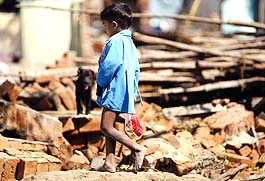 A young tsunami survivor carries a packet of food he received as relief in a hamlet on the beach in Cuddalore on Sunday.