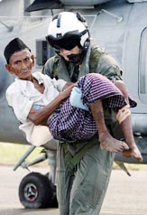 US Navy helicopter crewman at Indonesia's Banda Aceh airport carries an Acehnese man