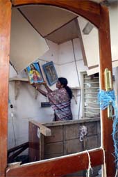 An Indian woman adjusts a picture in her house which was damaged by the tsunami in Kanniyakumari, on Tuesday. 