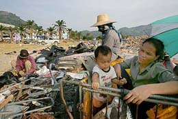 Thai residents pick up garbage from the houses damaged by tsunami at Patong, the entertainment district of Phuket, on Tuesday. 