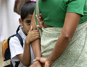 A Sri Lankan student with his mother as he arrives at his school for the first time after the tsunami hit the coastal city of Galle