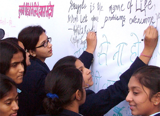 Schoolchildren write messages on a board for tsunami victims at a function on the birth anniversary of Swami Vivekananda, organised by the Visva Yuvak Kendra, at the National Stadium in New Delhi on Wednesday.