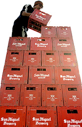 A Filipino store assistant stacks cases of San Miguel beer in Manila on Friday.