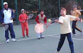 A young tennis player executes a shot under the guidance of tennis coach Gajendra Singh at the Chandigarh Lawn Tennis Association courts in Sector 10, Chandigarh