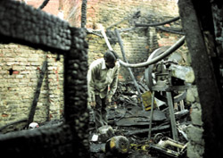 A man sifts through the gutted remains after a fire at Jhandewalan Extension in the Capital on Friday.