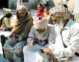 Surjan Singh tries to recognise his colleagues in a photo of his Army unit with his wife, Surinder Kaur, and elder brother, Gurmail Singh