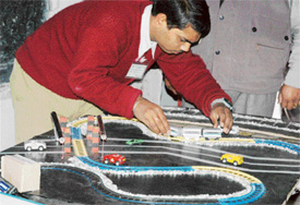 A student displays model of the railway track that stops train in case of any obstruction